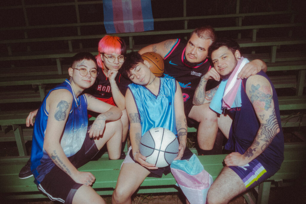 Basketball players with trans flag in the stands